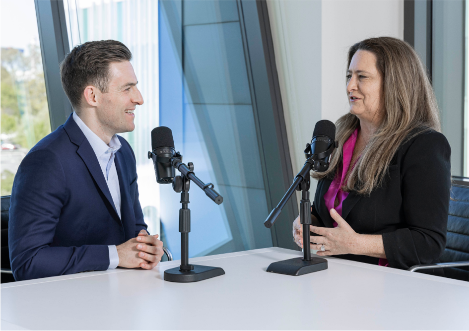 Lara Rhame and Andrew Korz talking talking into microphones for a podcast